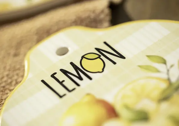 Geschenkgutschein mit Motiv eines dekorativen Schildes in Zitronenform mit Aufschrift ‚LEMON‘ und Zitronendesign