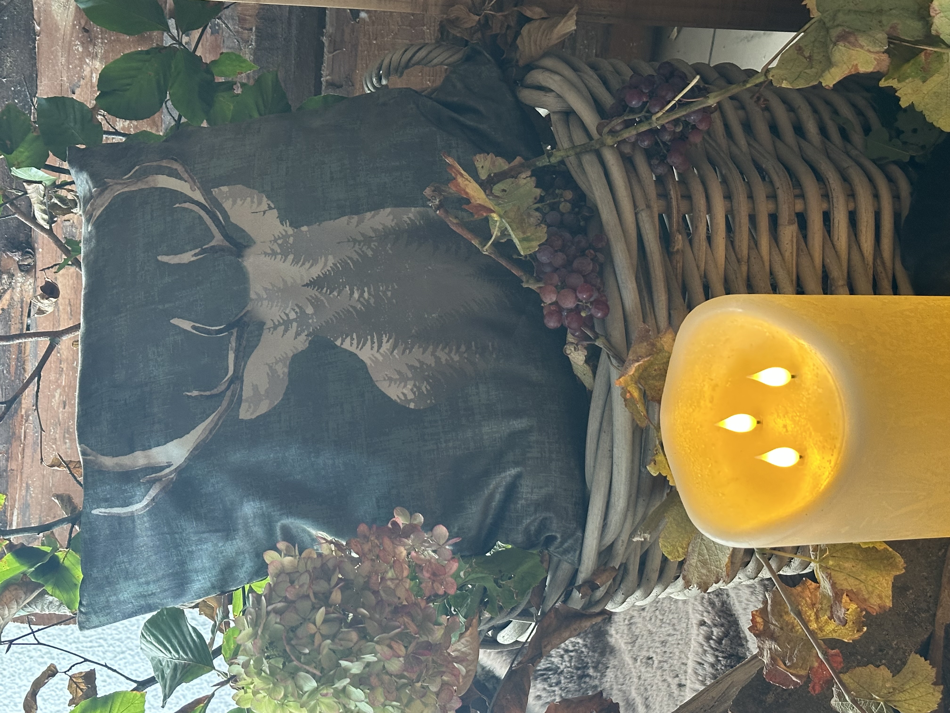 Wohntextilien: Kissen mit Hirschmotiv im Weidenkorb als herbstliche Dekoration im Landhausstil