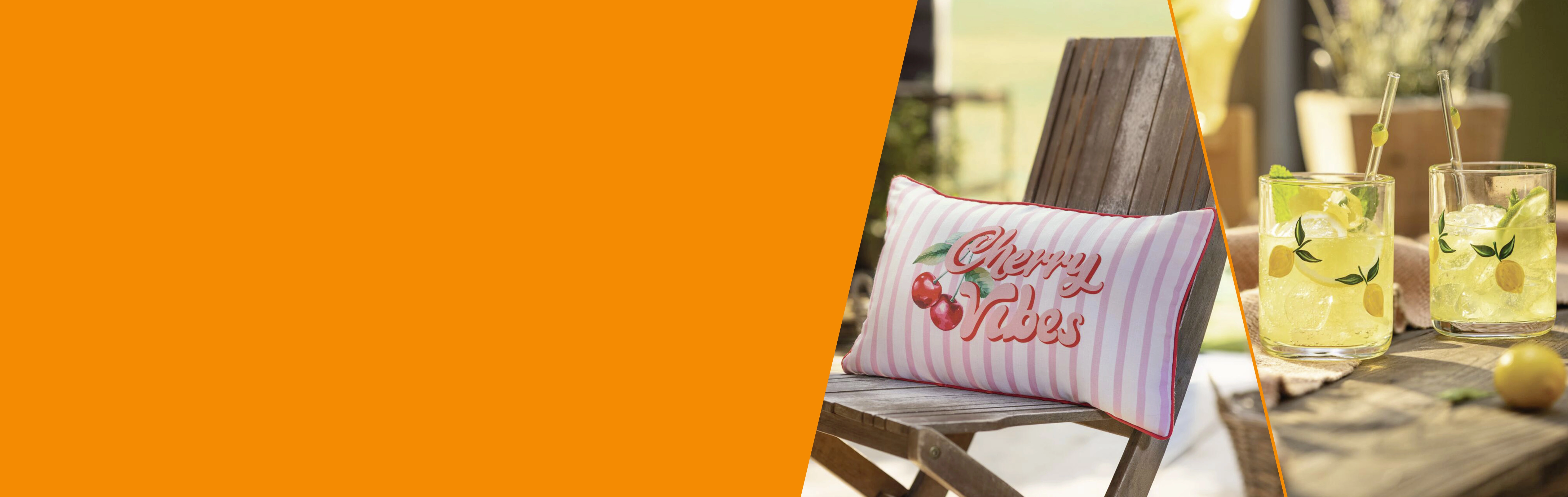 Sommerdeko: gestreiftes Kissen mit Kirschenmotiv und Zitronengetränke als Terrassendekoration