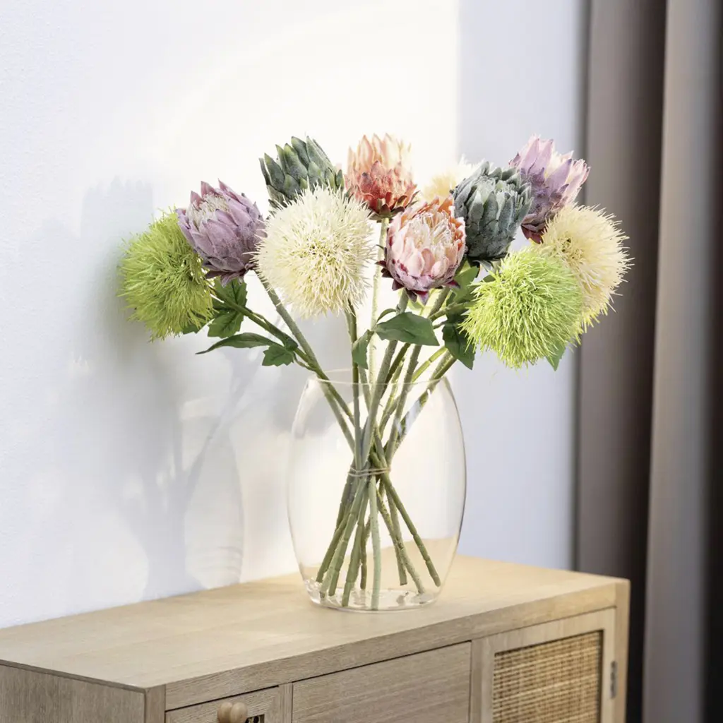 Bunter Protea-Strauß in einer Glasvase auf Sideboard