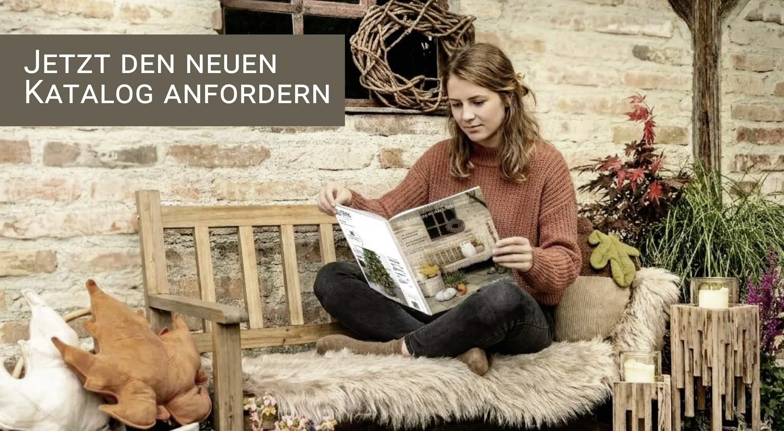 Katalogbestellung: herbstlich dekorierte Holzbank mit Wohnaccessoires und Person beim Lesen eines Deko‑Katalogs