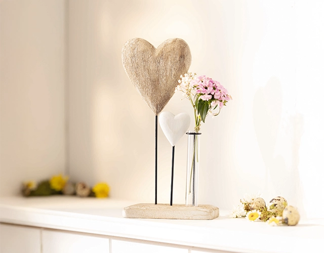 Herzdeko: Holzherz und weißes Herz mit rosa Blumen im Glas als romantische Tischdekoration