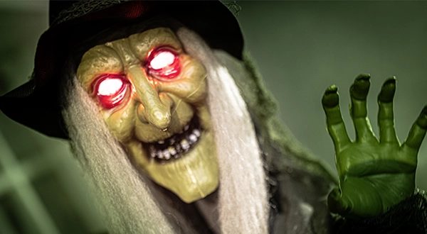 Halloween-Deko: gruselige Hexe mit Hut und leuchtenden Augen als schaurige Herbstdekoration