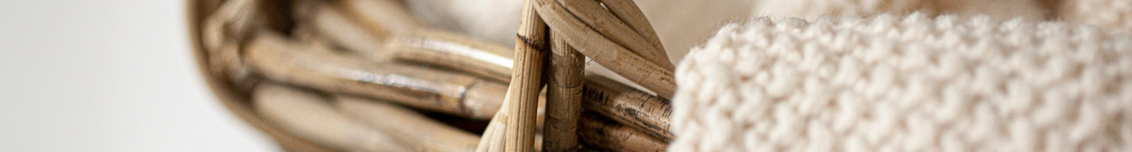 Aufbewahrungskörbe: naturfarbener Flechtkorb mit beiger Strickdecke als warme Wohnraumdeko