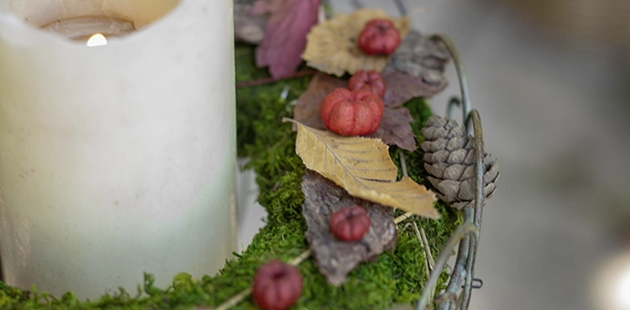 Herbstdeko: Kerze mit Moos, Blättern und kleinen Kürbissen als nostalgische Dekoration