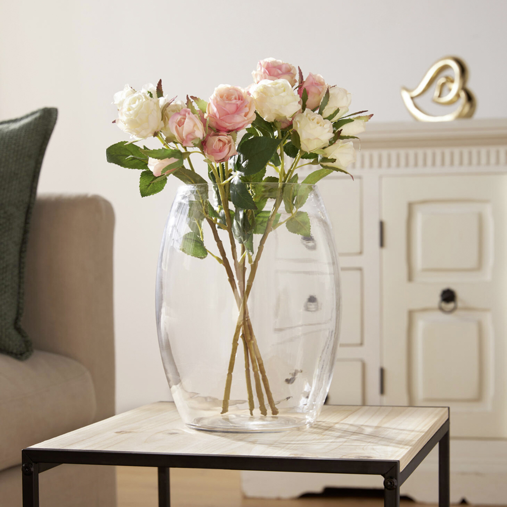Rosa und cremefarbene Rosen in großer Glasvase auf Beistelltisch