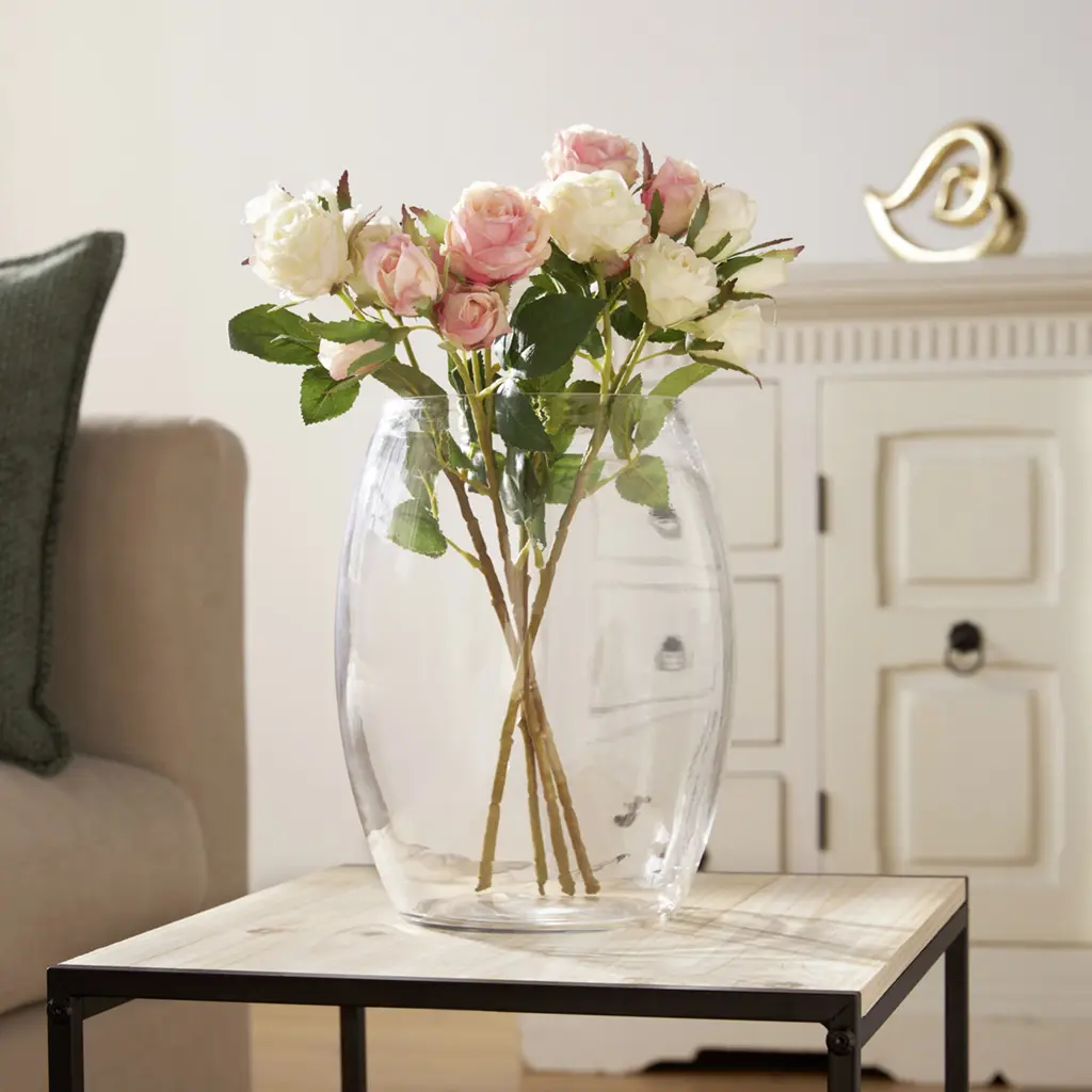 Rosa und cremefarbene Rosen in großer Glasvase auf Beistelltisch