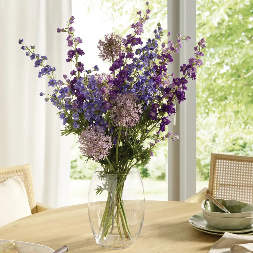 Violetter und rosa Blumenstrauß in einer Glasvase auf einem Holztisch