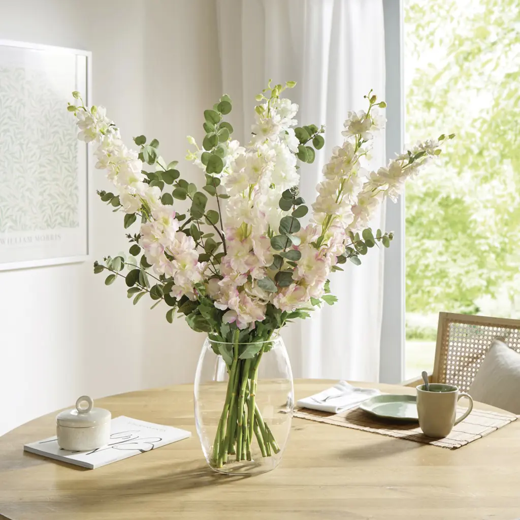 Heller Blumenstrauß aus weiß‑roséfarbigen Blüten und Eukalyptus in Glasvase