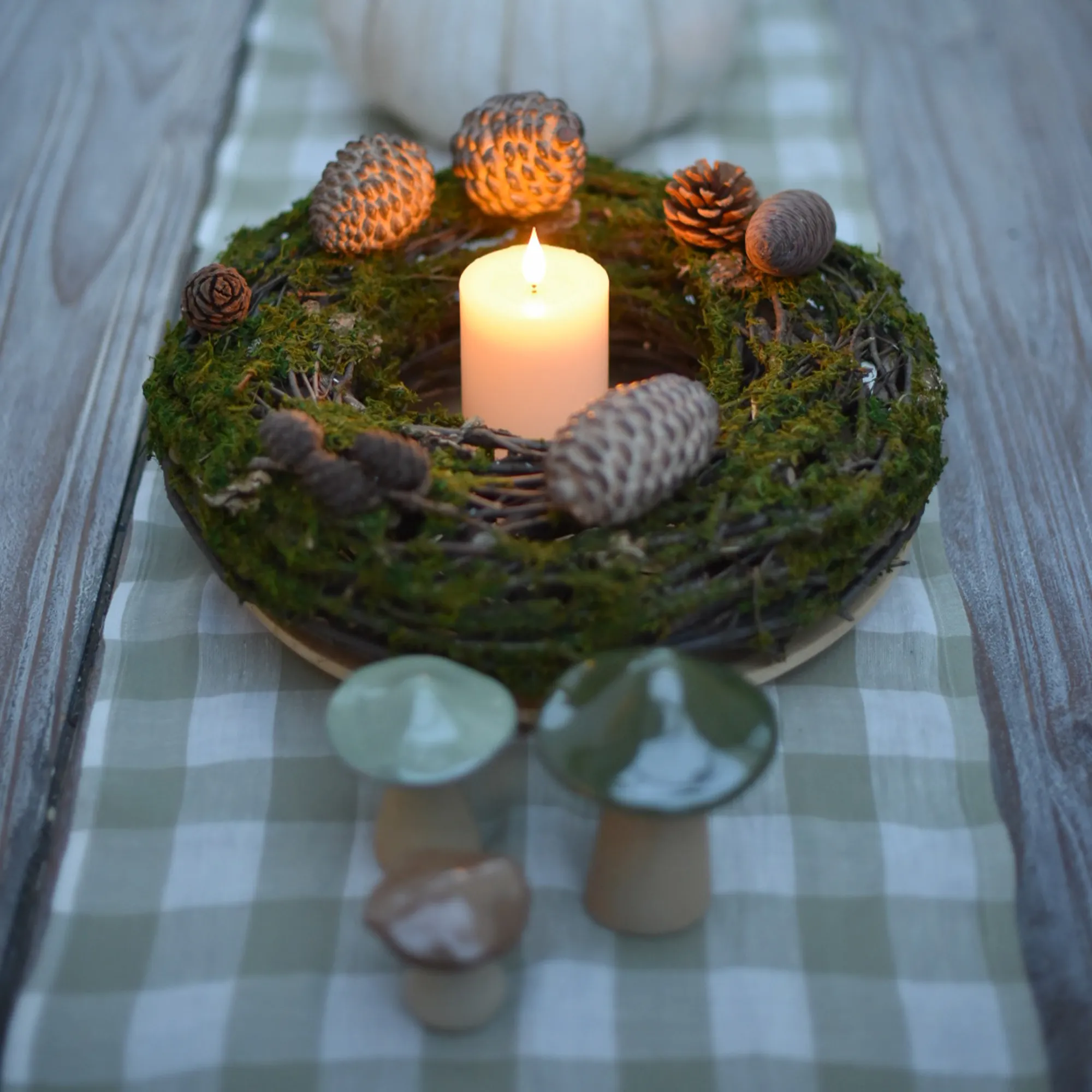 Herbstdeko: Mooskranz mit LED‑Kerze, Zapfen und Keramikpilzen als natürliche Tischdekoration