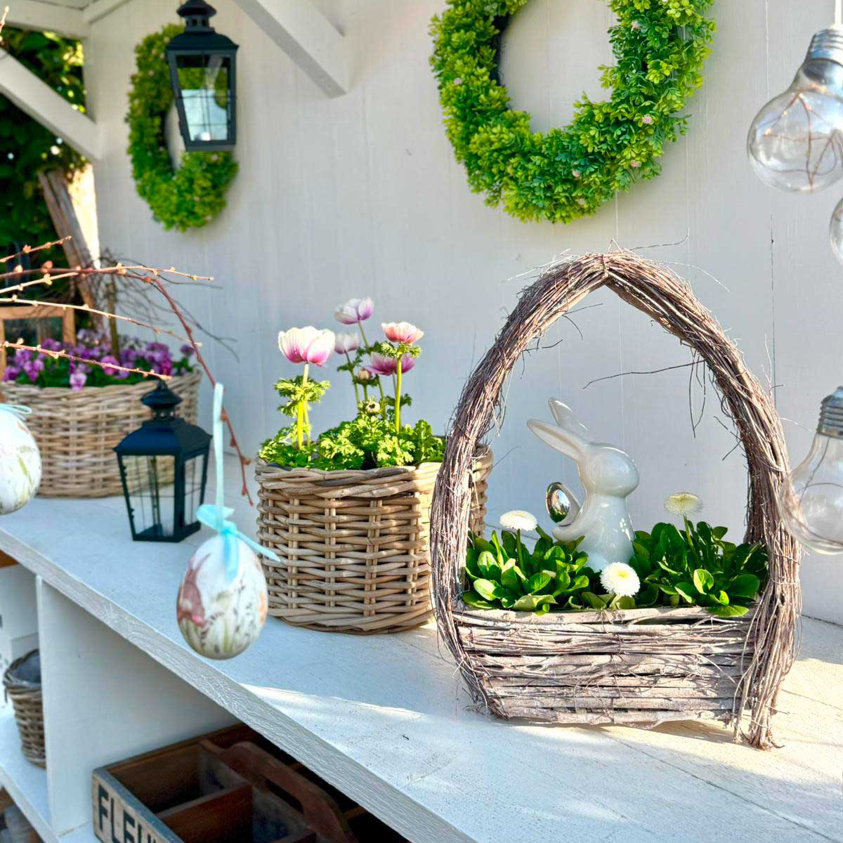 Osterdeko: Weidenkorb mit weißer Hasenfigur und Frühlingsblumen als natürliche Gartendeko