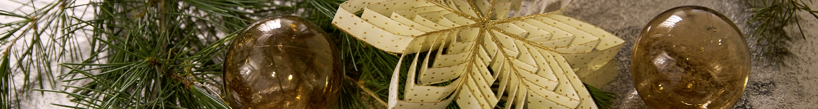 Weihnachtsdeko: goldene Papierblüte mit Christbaumkugeln und Tannenzweigen als Festtagsdekoration
