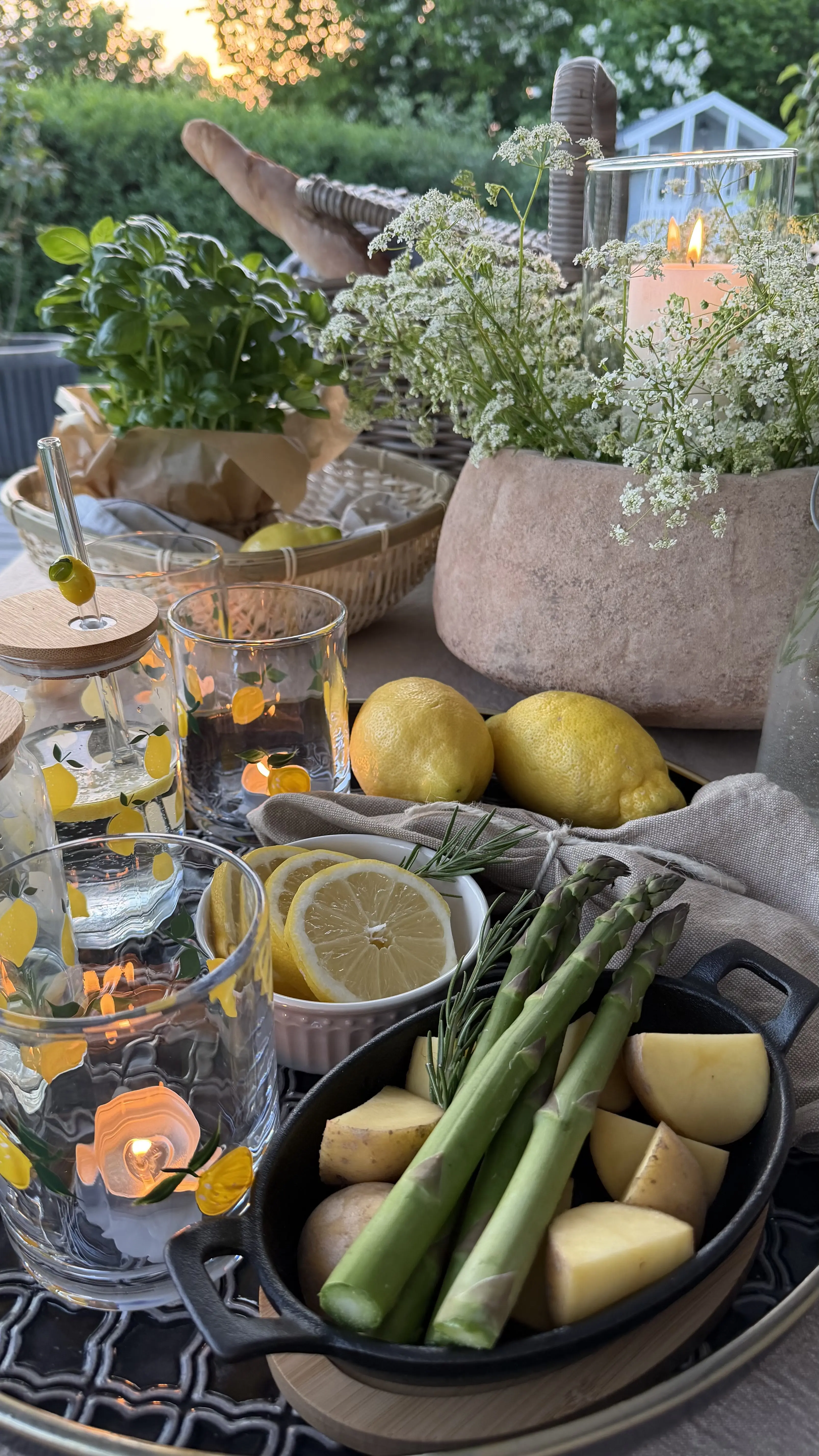 Tischdeko: Gartentisch mit Zitronen, Spargel, Gläsern und Kerzen als sommerliche Outdoor‑Dekoration