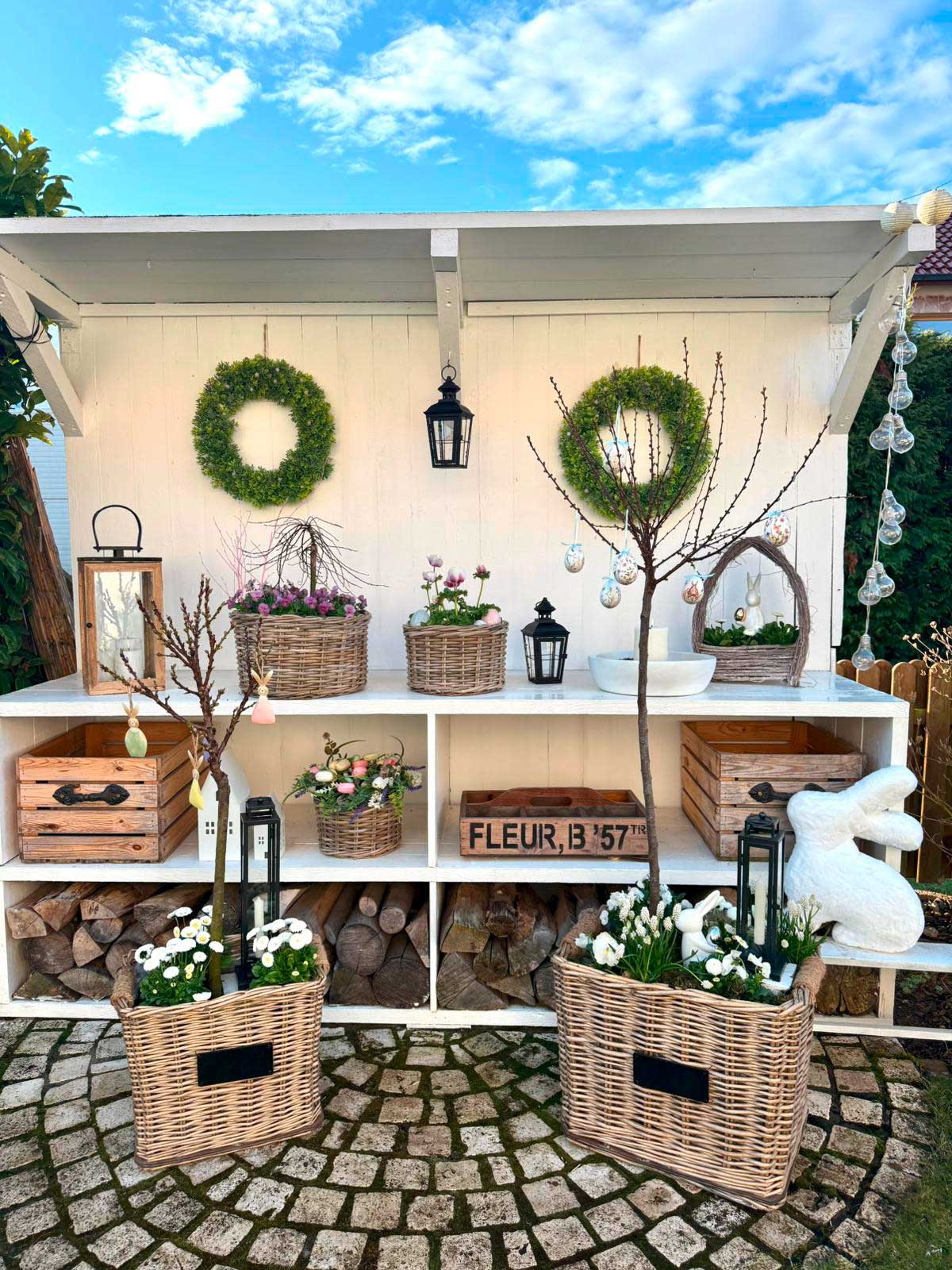 Frühlingsdeko: Weidenkörbe mit Blumen und grünen Kränzen als Gartendekoration