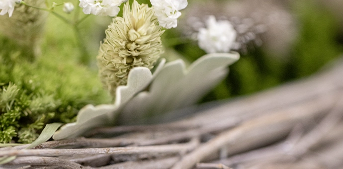 Naturdeko: geflochtene Zweige mit grünen Moosflächen und weißen Blüten als Frühlingsdekoration