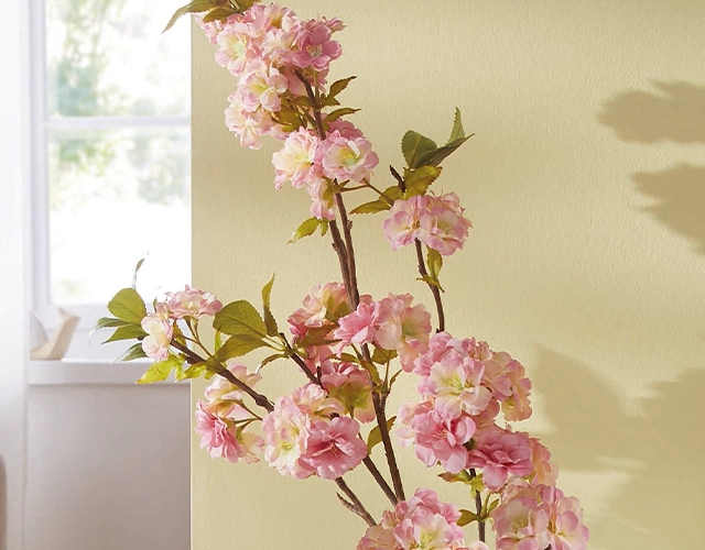 Kunstblumen: rosa Kirschblütenzweig mit grünen Blättern als frische Frühlingsdeko