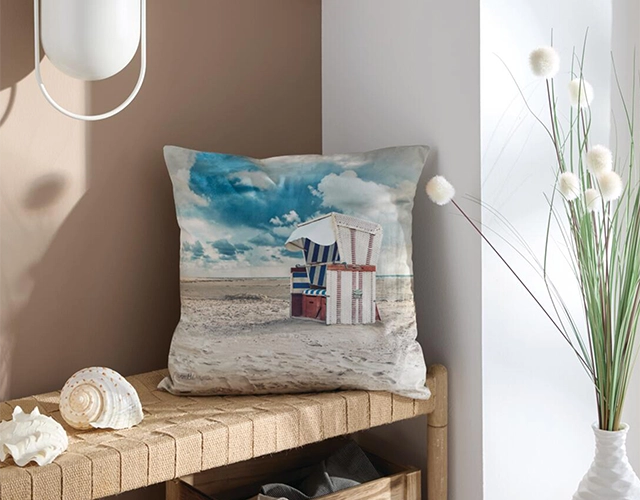 Wohntextilien: Kissen mit Strandkorbmotiv und Muscheln als maritime Wohnraumdekoration