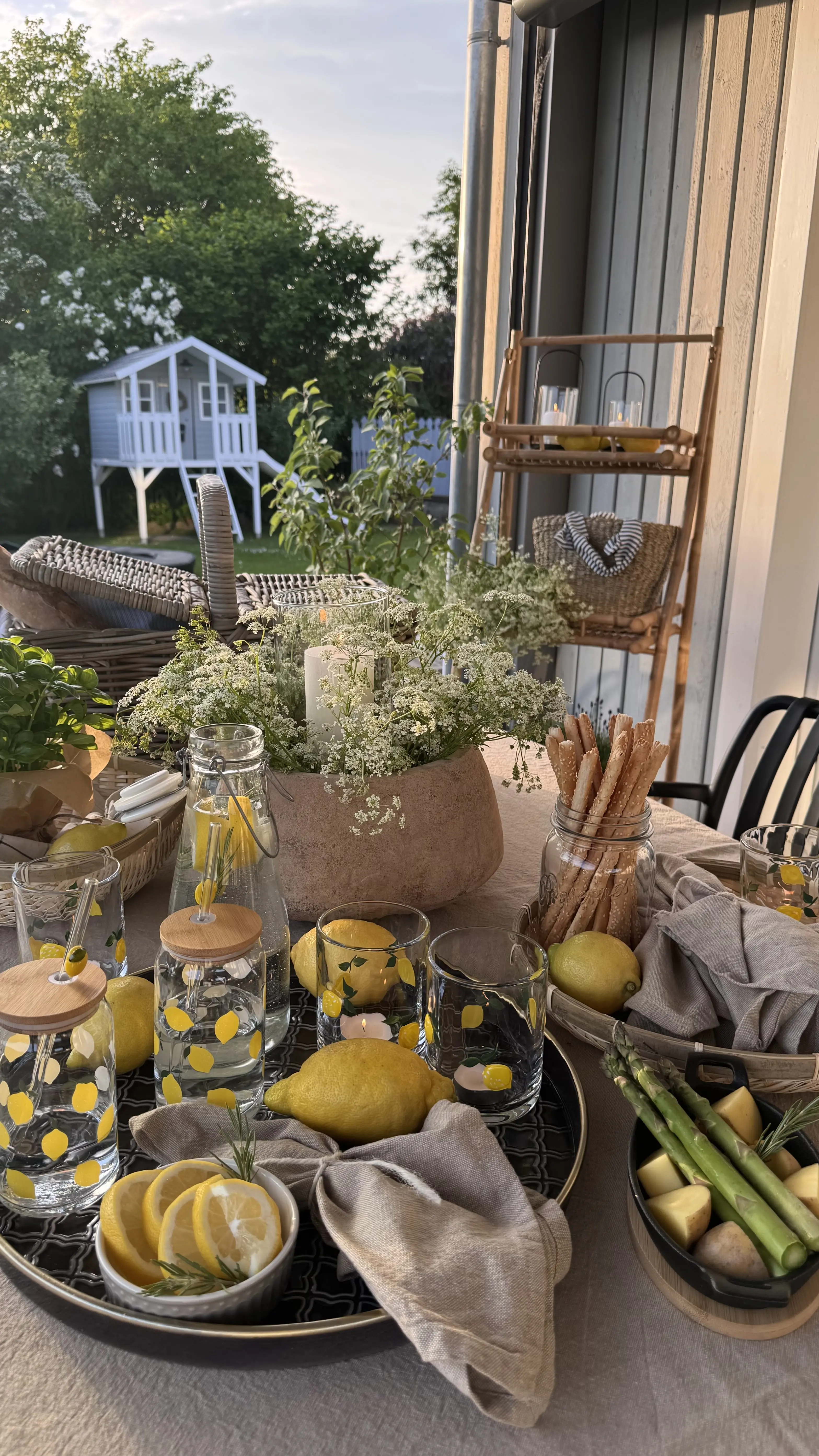 Tischdeko: sommerlich gedeckter Tisch mit Zitronen, Gläsern und Snacks im Garten