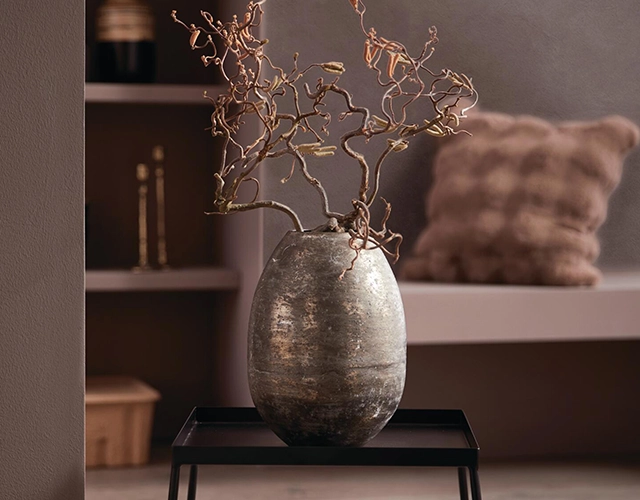 Wohnaccessoires: große graue Metallvase mit dekorativen Zweigen als moderne Tischdeko