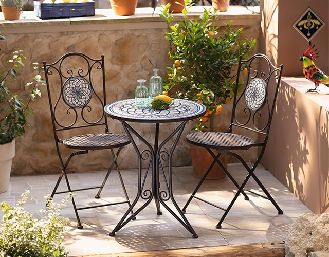 Gartendeko: Bistrotisch mit Metallstühlen, Zitronen und Glasflaschen als mediterrane Terrassendeko