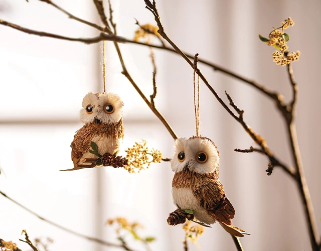 Herbstdeko: Eulenanhänger aus Naturmaterialien an Zweigen als dekorativer Herbstschmuck