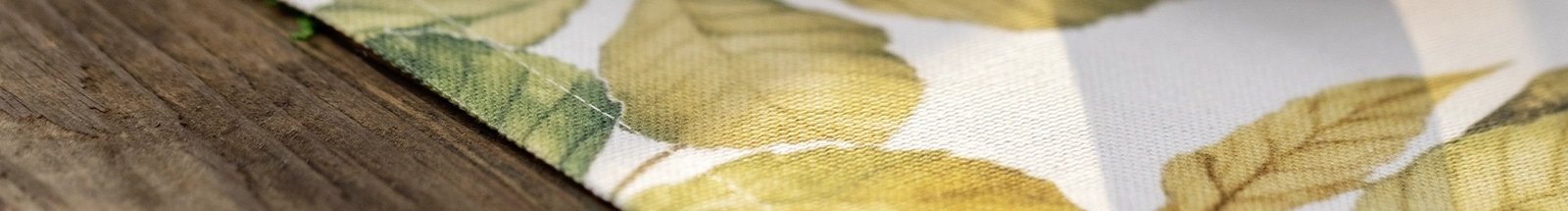 Wohntextilien: Stoff mit herbstlichem Blättermuster in Grün und Gold als saisonale Dekoration