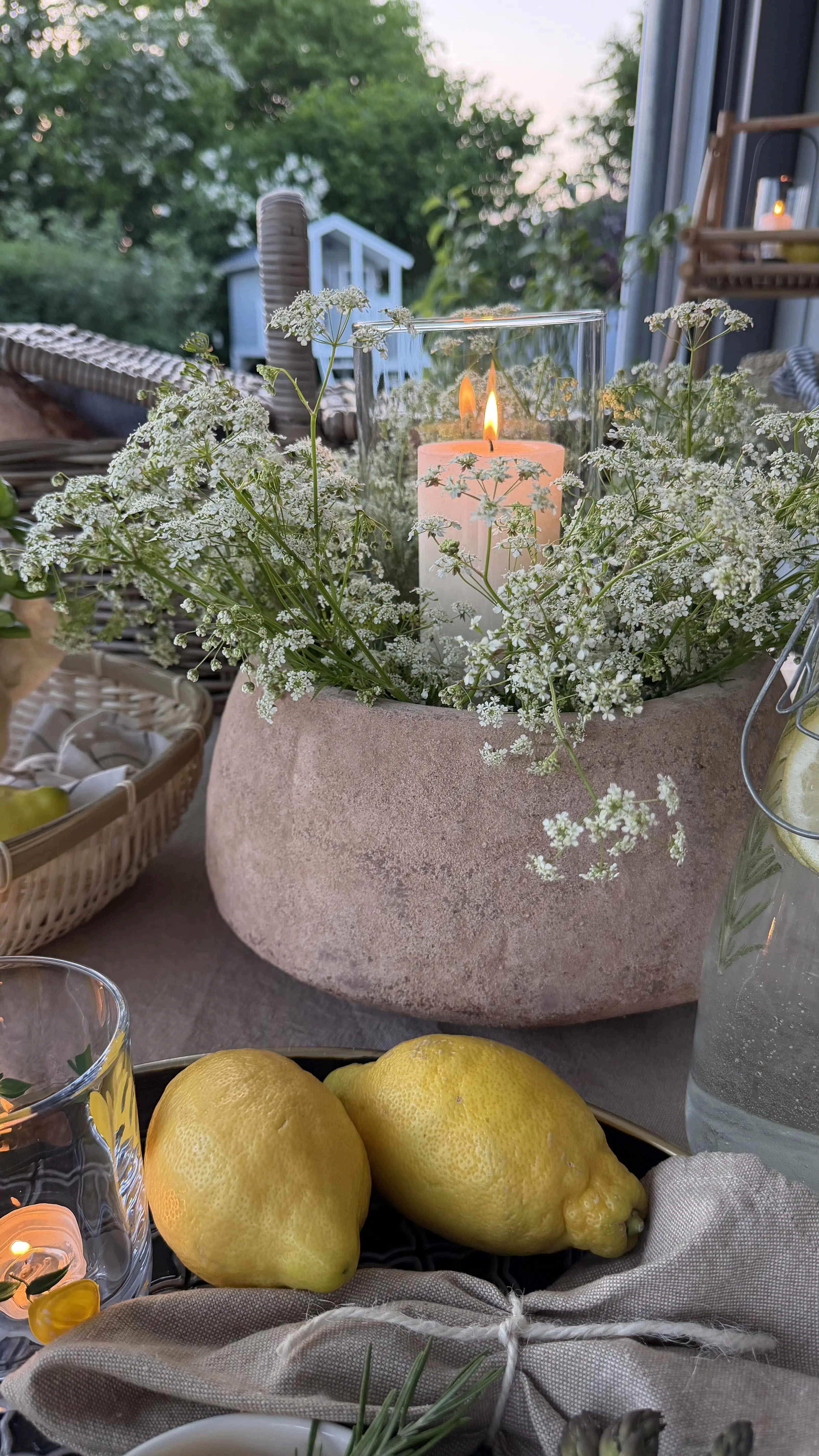 Gartendeko: Pflanzschale mit weißen Blumen und Kerze im Glas als stimmungsvolle Terrassendeko