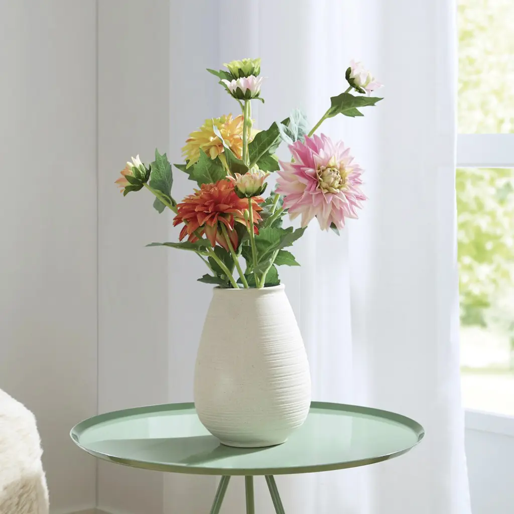 Bunter Dahlienstrauß in cremefarbener Vase auf rundem Tisch